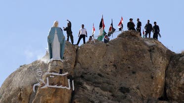  Members of the Syrian National Defence Forces (NDF) stand behind a statue of Virgin Mary perched on the cliffs overlooking the ancient Christian town of Maalula, 56 kilometers northeast of the Syrian capital Damascus, on June 13, 2015. (AFP)