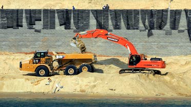 Bulldozers and trucks work on a new section of the Suez canal during a media tour in Ismailia, Egypt, Saturday, June 13, 2015. Work on a parallel waterway to allow two-way traffic on Egypt's Suez Canal will be finished in time to allow ships to transit for a gala inauguration at the key trade route on Aug. 6, officials said Saturday. President Abdel-Fattah el-Sissi ordered the new waterway to be dug in a single year, saying that the urgency of Egypt's economic situation meant the project could not wait for an originally planned three-year timetable. (AP Photo/Hassan Ammar)