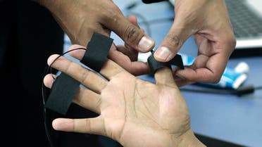 A polygraph examiner applies electrodes on the fingers of a student at the Latin American Polygraph Institute in Bogota, Colombia, on June 12, 2007. The polygraph is all the rage in deception-weary Colombia, with more than 300 businesses using the instrument to screen employees. The prime time TV show Nothing But the Truth rewards contestants for taking a lie detector exam and revealing intimate details of their lives.(AP Photo/Fernando Vergara)