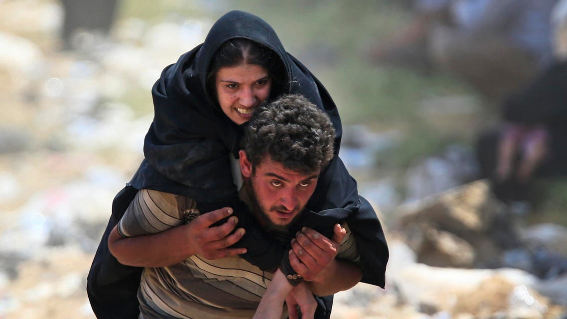 A Syrian refugee carries a sick woman on his back in Akcakale, southeastern Turkey, as they flee intense fighting in northern Syria between Kurdish fighters and ISIS militants, Monday, June 15, 2015. (AP)