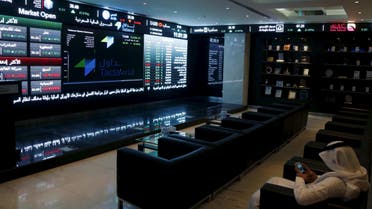 A trader uses his mobile as he monitors screens displaying stock information at the Saudi Stock Exchange (Tadawul) in Riyadh June 15, 2015. (Reuters)