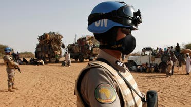 Two UNAMID peacekeepers patrol by trucks loaded with new arrivals of displaced Sudanese at Zamzam refugee camp, outside the Darfur town of al-Fasher, Sudan, Monday, March 23, 2009.