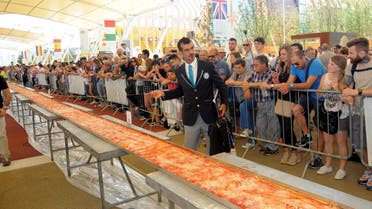 Judge of the Guinness World Records Lorenzo Veltri checks the length of a pizza at the Expo 2015 world's fair in Rho, near Milan, Saturday, June 20, 2015.