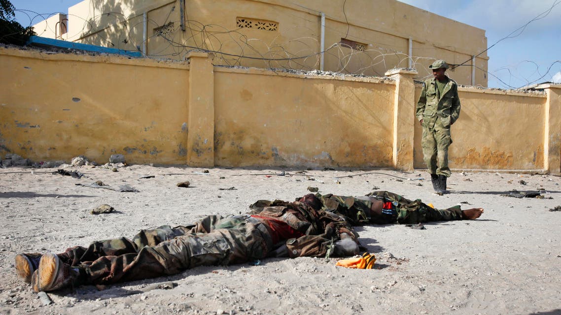A Somali soldier walks past the bodies of two suspected al-Shabab fighters who were killed while engaging in a car bomb attack in the capital Mogadishu, Somalia Sunday, June 21, 2015.