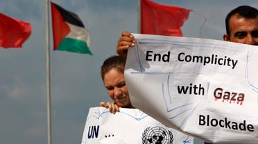 Palestinian and foreign activists hold placards in front of Palestinian and Turkish flags during a rally to show their support for two boats carrying 27 civilians from various countries attempting to reach the Gaza Strip, in the sea port of Gaza City Friday, Nov. 4, 2011. AP