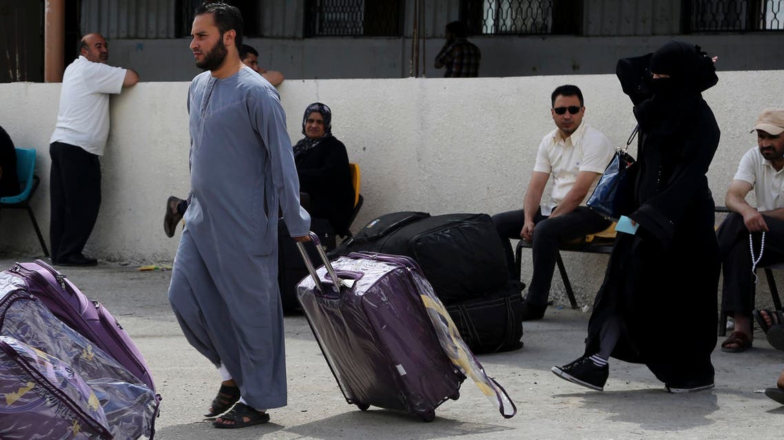 A Palestinian couple push their luggage heading to the bus as others wait to cross to the Egyptian side of the Rafah border crossing, in the southern Gaza Strip, Tuesday, June 23, 2015. (AP)