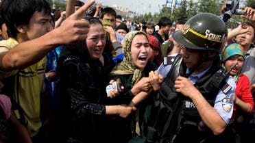 Uighur women grab a police officer as they protest in front of journalists visiting the area in Urumqi, China on July 7, 2009. (File Photo: AP)