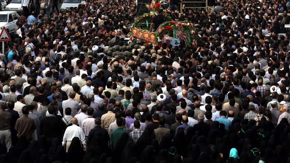 Iranian mourners touch the coffins of Mohammad Hamidi, Hasan Ghafari and Ali Amrai, members of the Islamic Republic's Revolutionary Guards reportedly killed in Syria, during their funeral in Tehran on June 25, 2015. (AFP)