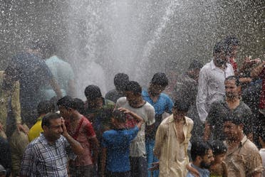 People cool off from the heat as they are sprayed with water jetting out from a leaking water pipeline in Karachi, Pakistan, June 25, 2015. (Reuters)