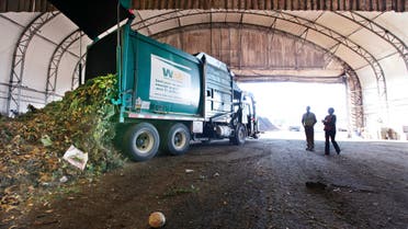 visitors watch as a truck dumps compost materials inside a receiving area at the Cedar Grove processing facility in Everett, Wash. AP