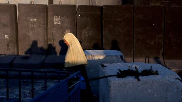 A Palestinian woman walks by the Israeli separation barrier on her way to Jerusalem through the Qalandia security checkpoint, on the outskirts of the West Bank city of Ramallah, Friday, July 4, 2014. (AP)