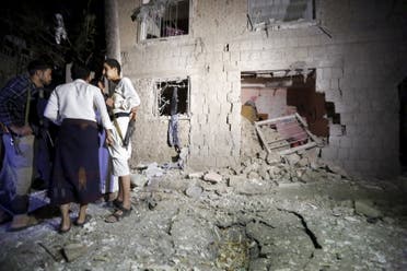 People stand next to a damaged house at the site of a car bomb attack in Yemen's capital Sanaa June 29, 2015.