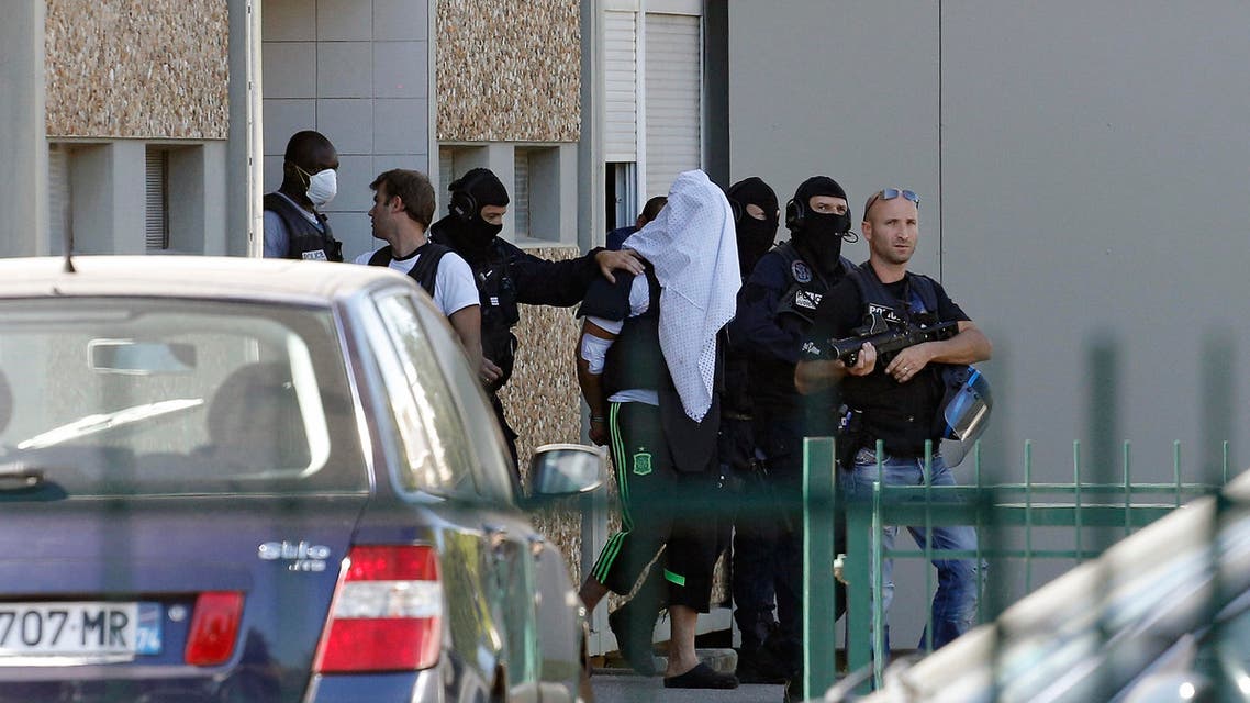 The suspect in the beheading of a businessman, Yassine Salhi, a towel over his head to mask his face, is escorted by police officers as they leave his home in Saint-Priest, outside the city of Lyon, central France, Sunday, June 28, 2015.