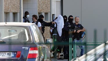 The suspect in the beheading of a businessman, Yassine Salhi, a towel over his head to mask his face, is escorted by police officers as they leave his home in Saint-Priest, outside the city of Lyon, central France, Sunday, June 28, 2015. 