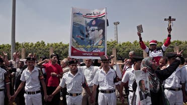 Security forces stand guard as mourners hold a poster of Egyptian President Abdel-Fattah el-Sissi, a cross and a Quran, during the funeral of Prosecutor General Hisham Barakat, killed in bomb attack a day earlier, outside the Hussein Tantawi Mosque in Cairo, Egypt, Tuesday, June 30, 2015. AP