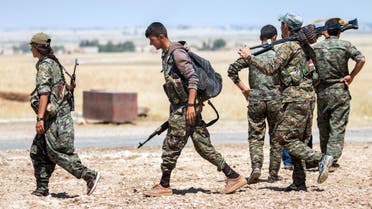Kurdish People's Protection Units fighters walk with their weapons at the eastern entrances to the town of Tal Abyad in the northern Raqqa countryside, Syria