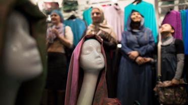 Russian muslim women wearing the Islamic headscarf stand behind a mannequin as they come to attend a celebration of the World Hijab Day in a new store "Irada" in Moscow, Russia, Sunday, Feb. 1, 2015. (AP Photo/Alexander Zemlianichenko)