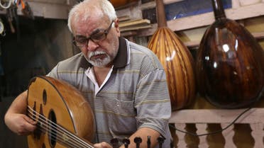In this photo taken Saturday, June 20, 2015, Mahmoud Abdulnabi tries out an oud, an Arabic instrument related to the lute, at his workshop in Baghdad, Iraq. “The oud is different than other musical instruments,” said Abdulnabi, who has crafted ouds played by some of Iraq’s best known musicians, many of whom look down from headshots on the walls. ”If you feel joyful, it can play your joy. If the circumstances are sad it can play your sorrow and... help to empty whatever is in your chest.” (AP Photo/Hadi Mizban)