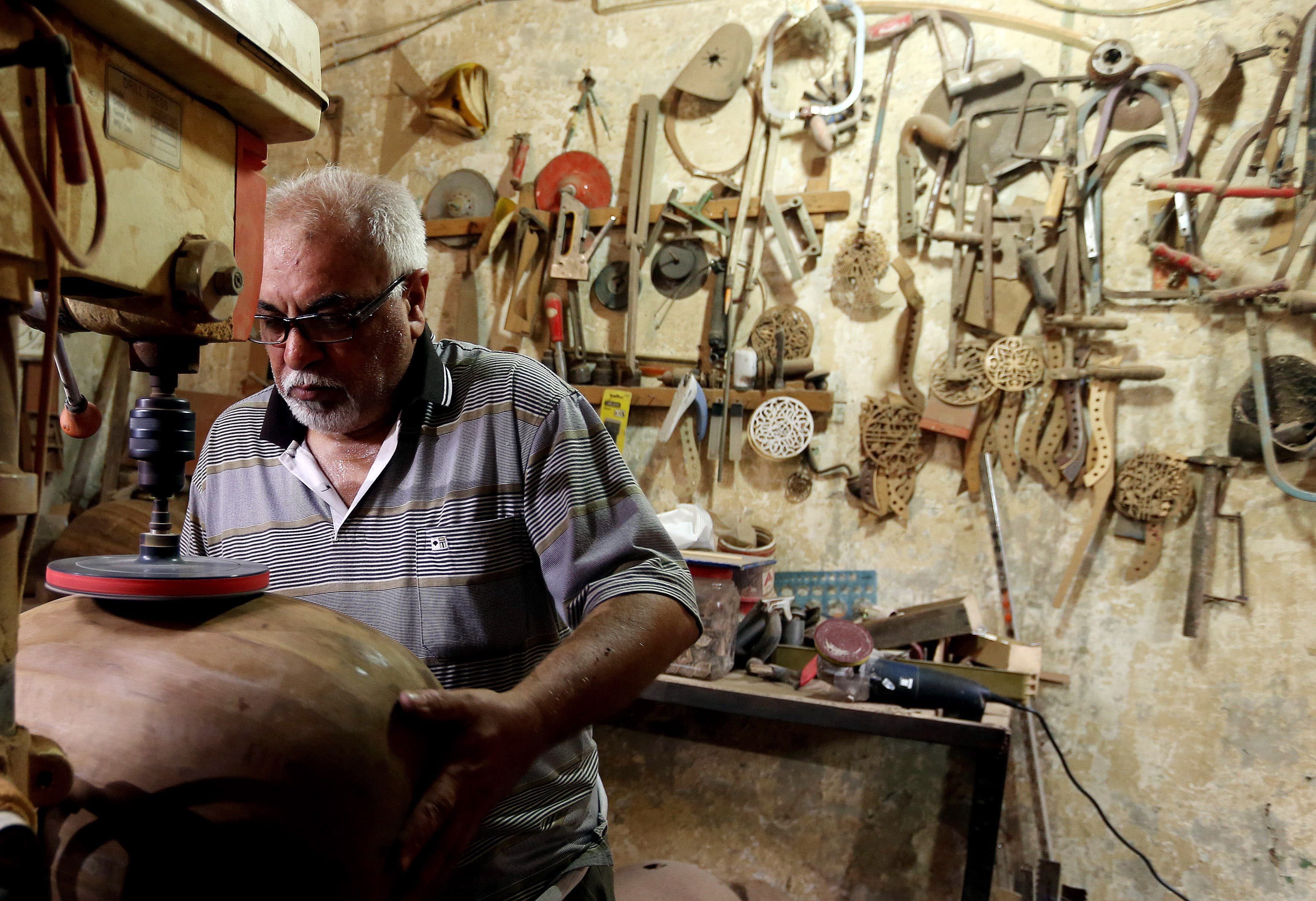 In this photo taken Saturday, June 20, 2015, Mahmoud Abdulnabi works on an oud, an Arabic instrument related to the lute, at his workshop in Baghdad, Iraq.(AP Photo/Hadi Mizban)