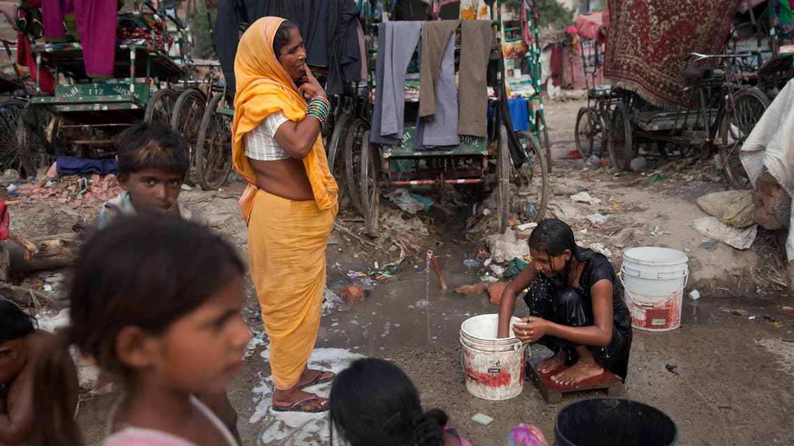 An Indian girl bathes beside a woman brushing her teeth at a shanty area in New Delhi, India, Tuesday, June 30, 2015. There is no direct supply of potable water at homes in most of the poor neighborhoods in the country and people have to depend on regulated supply of water from public taps erected on roadsides, with a single tap catering to hundreds of households. (AP Photo/Tsering Topgyal)