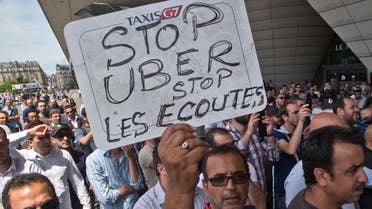A striking taxi driver holds a placard which read, "Stop Uber, Stop listening," referring to the new US spying report in France, during a taxi drivers demonstration in Paris, France, Thursday, June 25, 2015.