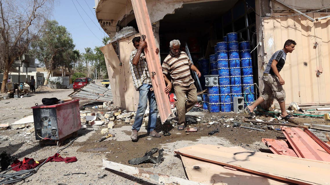 Civilians pass by the site of a car bomb attack in Baghdad's northern neighborhood of Shaab, Iraq, Thursday, June 25, 2015. AP
