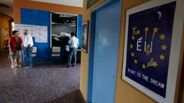A couple arrives to vote as a policeman stands under Acropolis photograph at a polling station in Athens, Sunday, July 5, 2015. 