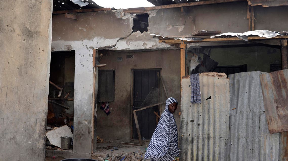 A girl walks past a house damaged in Saturday's rocket propelled grenades by Islamic extremist in Maiduguri, Nigeria, Sunday, May 31, 2015. A bomb injured four people in a market Sunday in Maiduguri, a day after the northeastern Nigerian city was hit by a suicide bomber who killed 16 in a mosque. (AP Photo/Jossy Ola)