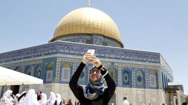 A Palestinian woman takes a photo next to the Dome of the Rock Mosque in the Al Aqsa Mosque compound, on the third Friday of the Muslim holy month of Ramadan, in Jerusalem's old city, Friday, July 3, 2015.