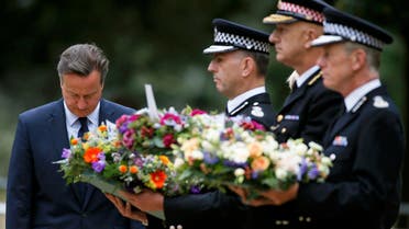 Britain's Prime Minister David Cameron bows as he stands with police officers after laying a wreath at the memorial to victims of the July 7, 2005 London bombings, in Hyde Park, central London, Britain July 7, 2015. Britain fell silent on Tuesday to commemorate the 10th anniversary of attacks targeting London public transport which killed 56 people, the first suicide bombings by Islamist militants in western Europe. REUTERS/Peter Nicholls TPX IMAGES OF THE DAY