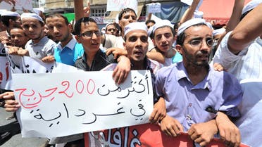 Hundreds of demonstrators of the Berber community stage a protest in front of a walled area where Algier's newspapers are headquartered in support of Berbers in the southern Ghardaia region where at least 22 people have died in ethnic unrest, in Algiers, Algeria, Wednesday, July 8, 2015. Authorities say ethnic clashes have left at least 22 people dead around Algeria's southern oasis city of Ghardaia, more than 600 kilometers (375 miles) south of Algiers, prompting the president to call an urgent security meeting. The Berbers and the Arabs in Ghardaia had for centuries lived together in harmony, but tensions started in late 2013 when a Berber shrine was vandalized. Poster reads in read : 200 wounded people. (AP Photo/Sidali Djarboub)