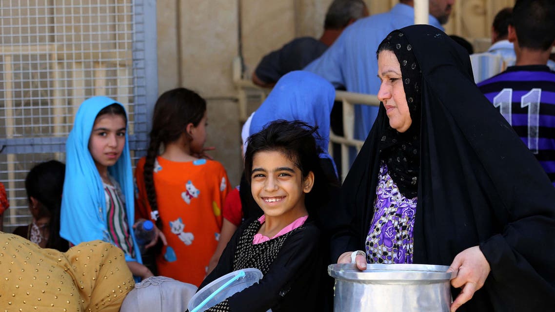 Iraqi women and children, most of them refugees, wait for free food being distributed for Iftar, the meal after fasting, at the Abdul Khader al-Kilani mosque in Baghdad, Iraq, Tuesday, June 23, 2015. AP