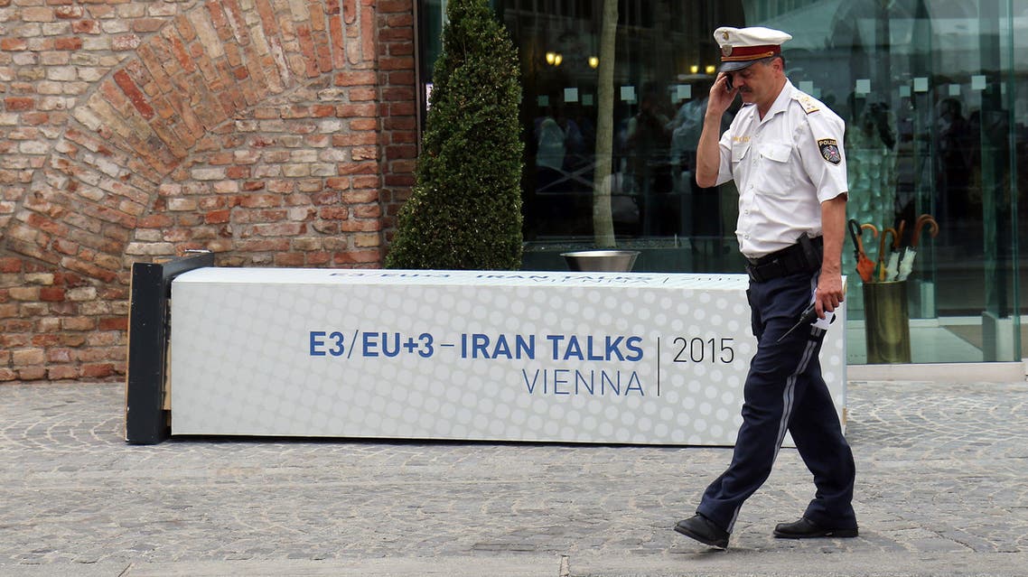 A Police officer walks past a fallen poster for the Iran talks in front of at Palais Coburg where closed-door nuclear talks with Iran take place in Vienna, Austria, Monday, July 6, 2015. (AP)