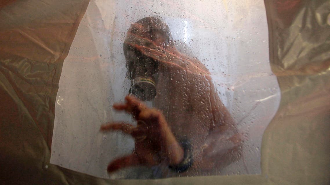 A crew member of the Danish warship Esbern Snare enters a decontamination shower wearing a gas mask during drills in 2014 when two cargo ships picked up more than 1,000 tons of Syrian chemical agents. (File: AP)