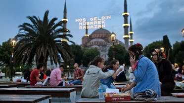 People break their fast backdroped by the the iconic Sultan Ahmed Mosque, better known as the Blue Mosque, decorated with lights marking the month of Ramadan, in the historic Sultanahmet district of Istanbul, Turkey, Thursday, June 18, 2015. AP