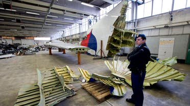 Dutch military police stand next to parts of the wreckage of the Malaysia Airlines Flight 17, displayed in a hangar at Gilze-Rijen airbase, Netherlands, Tuesday, March 3, 2015. AP