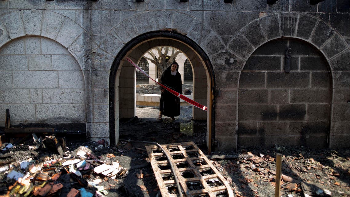 A nun surveys heavy damage at the Church of the Multiplication after a fire broke out in the middle of the night near the Sea of Galilee in Tabgha, Israel, Thursday, June 18, 2015. Israel police spokesman Micky Rosenfeld said police are investigating whether the fire was deliberate and are searching for suspects. A passage from a Jewish prayer, calling for the wiping out of idol worship, was found scrawled in red spray paint on a wall outside the church. (AP Photo/Ariel Schalit)