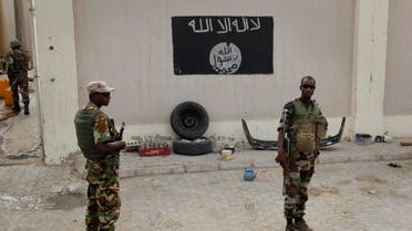 Chadian soldiers stand at a checkpoint in front of a Boko Haram flag the Nigerian city of Damasak, Nigeria, Wednesday March 18, 2015. 
