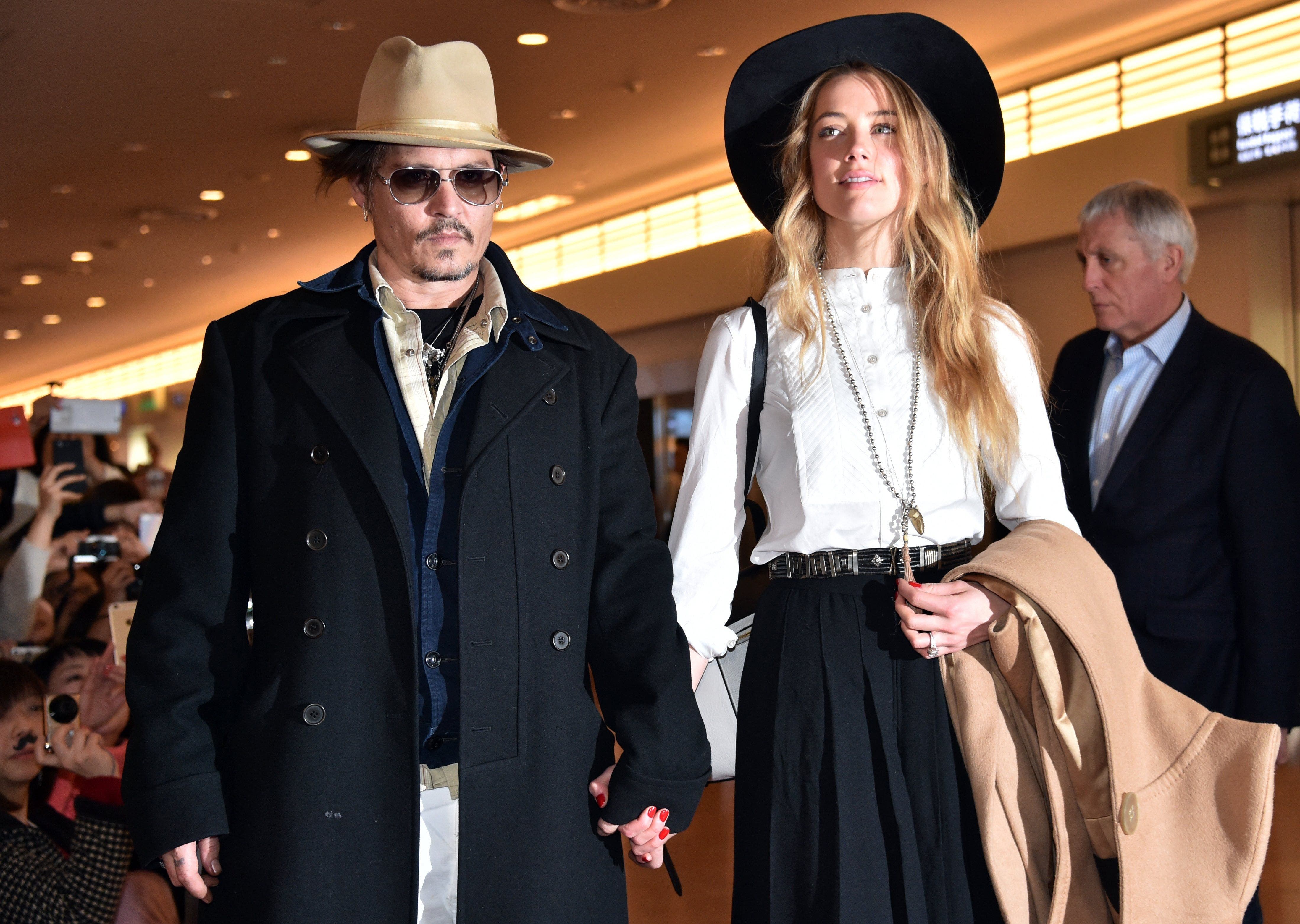 This file photo taken on January 26, 2015 shows US actor Johnny Depp (L) accompanied by his wife, US actress and model Amber Heard (R) after their arrival at Tokyo International Airport. (AFP)