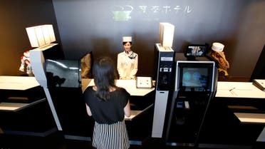 A receptionist robot, top center, accompanied by two other robots, greets a hotel employee demonstrating how to check in the new hotel, aptly called Henn na Hotel or Weird Hotel, in Sasebo, southwestern Japan, Wednesday, July 15, 2015