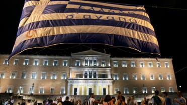 Anti-austerity protesters lift a Greek flag in front of the Greek Parliament in Athens, Greece July 15, 2015. REUTERS