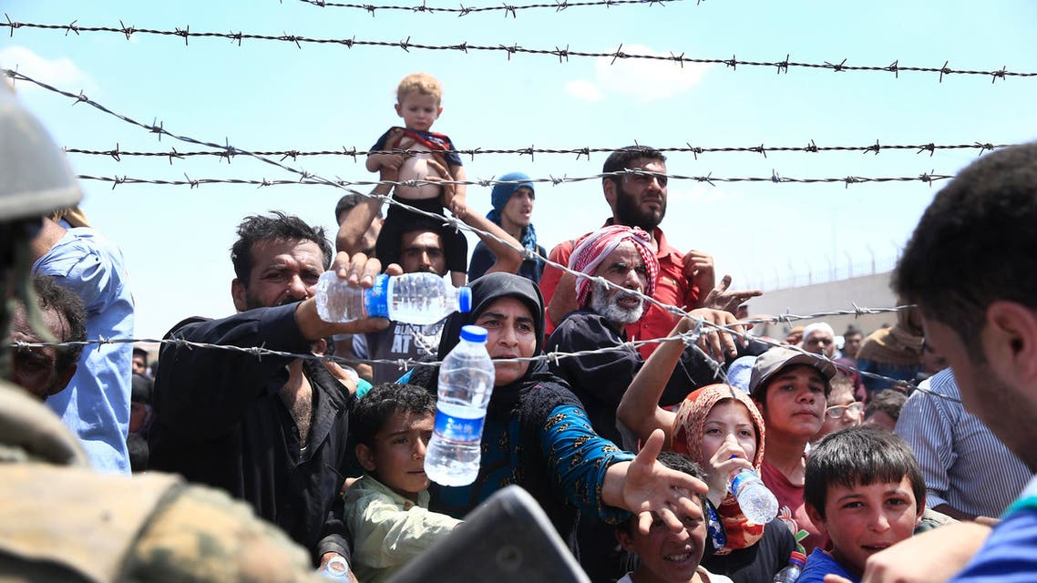 Syrian refugees receive water while they mass at the Turkish border as they flee intense fighting in northern Syria between Kurdish fighters and Islamic State militants in Akcakale, southeastern Turkey, Monday, June 15, 2015. AP