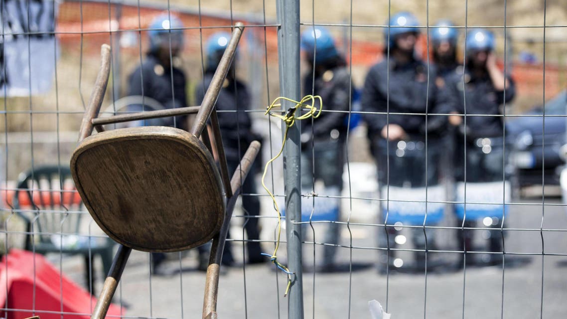Italian policemen in riot gear stand as residents and far right demonstrators protest against a migrants' arrival in the area in Rome, Friday, July 17, 2015. (Massimo Percossi/ANSA via AP)