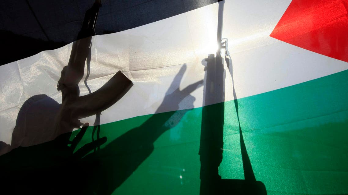 The shadow of a gunman from the Popular Front for the Liberation of Palestine is cast on a Palestinian flag as he flashes the victory sign, in the Ein el-Hilweh Palesinian refugee camp near Sidon, Lebanon. AP
