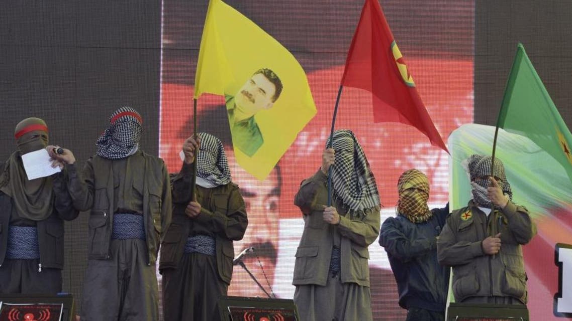 Masked supporters demonstrate with some thousands of supporters, not pictured, waving various PKK flags and images of jailed Kurdish rebel leader Abdullah Ocalan, left, in southeastern Turkish city of Diyarbakir, Turkey, Thursday, March 21, 2013 (AP)