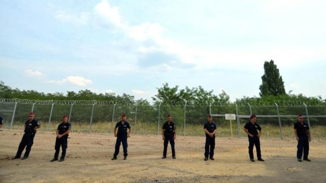 Hungarian soldiers stand in front of the first completed elements of the 150 meter-long fence on the border with Serbia