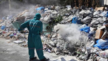 A waste management worker covers a pile of garbage using white pesticide in the Palestinian refugee camp of Sabra in Beirut, Lebanon, Friday, July 24, 2015.