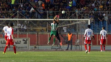 Jassim Mohammed of Wasat Oil, center, fights for the ball with Air Force football club goalkeeper Fahad Talib during their final soccer match of the Iraqi National League at the al-Shaab stadium in Baghdad, Iraq, Saturday, July 11, 2015. AP 