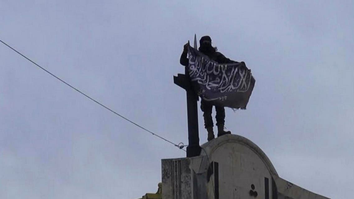 FILE - In this file photo posted on the Twitter page of Syria's al-Qaida-linked Nusra Front on Saturday, March 28, 2015, which is consistent with AP reporting, a fighter from Syria's al-Qaida-linked Nusra Front holds his group flag in Idlib province, north Syria. In the span of a month, a coalition of Syrian insurgents has routed government forces across the country's northwest, flushing them out of strongholds in a string of embarrassing loses for President Bashar Assad. (Al-Nusra Front Twitter page via AP, File)