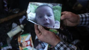 A man shows a picture of 18-month-old Palestinian toddler Ali Saad Dawabsha who died when his family house was set on fire by alleged Jewish extremists in the West Bank village of Duma. (AFP)